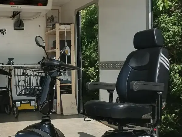 Elscooter med afmonteret hjul på rampen ved værkstedsbilen – handicapscooter