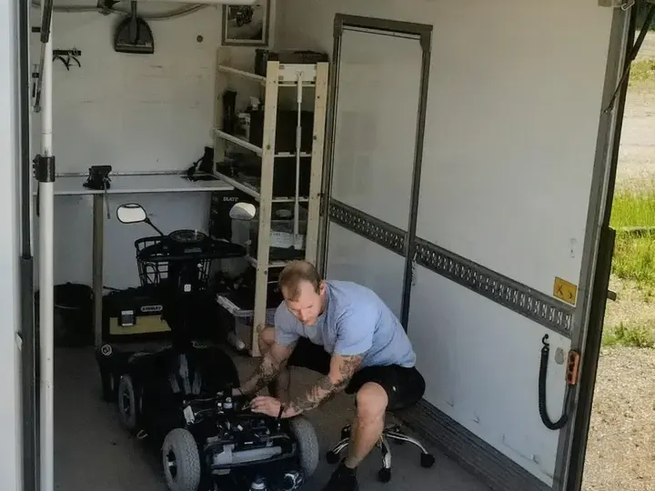 Indefra HalleCares mobile værksted, hvor en mekaniker arbejder på en elscooter – handicapscooter
